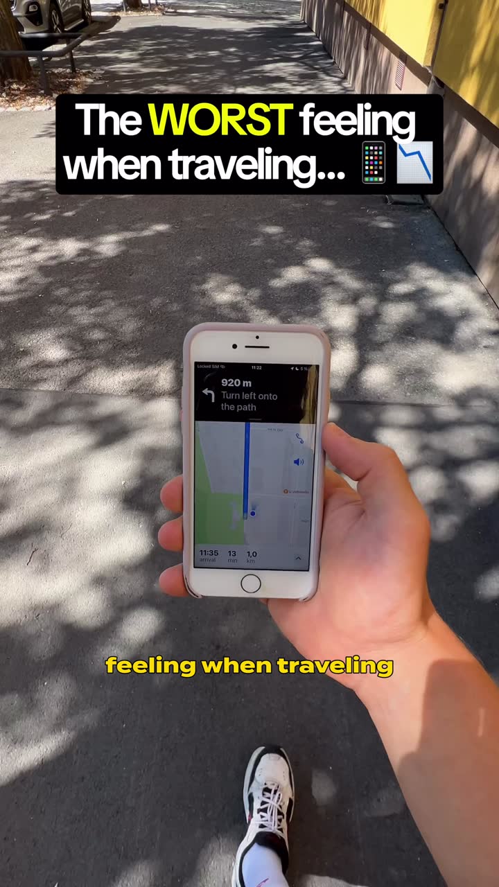 POV shot walking outdoors holding a phone at 5 percent battery, hook text reading: The worst feeling when traveling